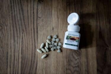 Frascos de suplementos de hierro junto a alimentos ricos en hierro para anemia.