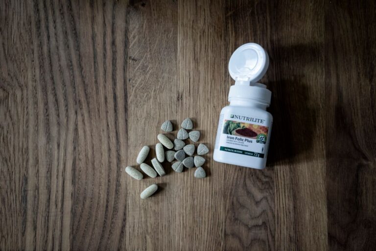 Frascos de suplementos de hierro junto a alimentos ricos en hierro para anemia.
