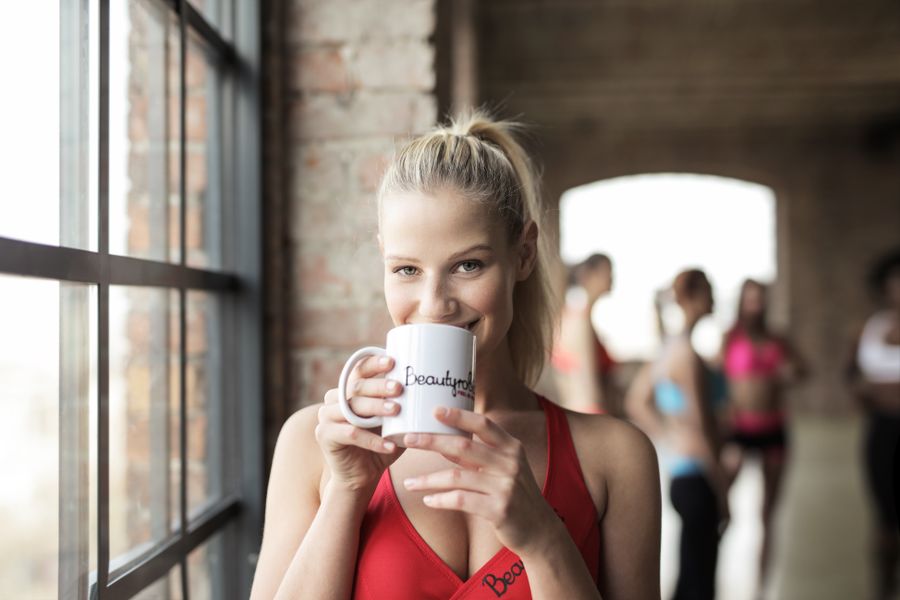 Mujer sonriente con taza en sesión fitness